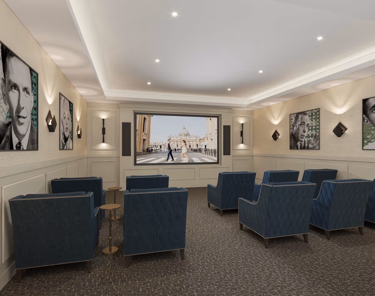 A comfortable media/theater room with blue upholstered chairs arranged in rows facing a large screen, neutral paneled walls with framed portraits, and recessed ceiling lights.