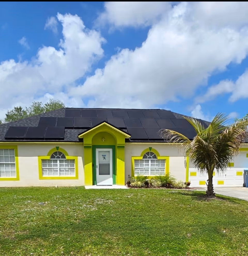 Front exterior of a single-story facility with solar panels, lime-green trim, and a palm tree.