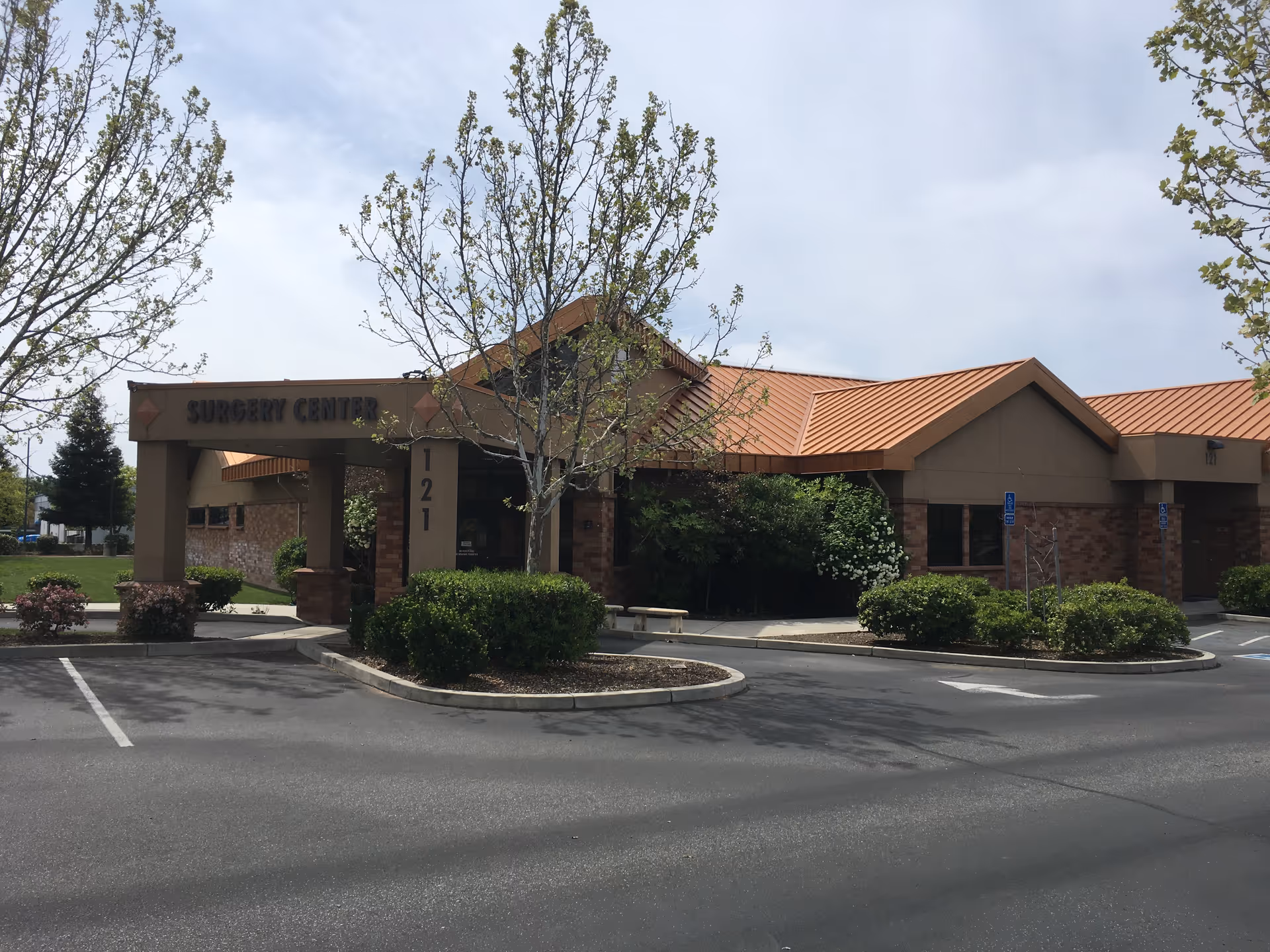 Skyway Surgery Center exterior with brick walls, tan roof, and surrounding landscaping.