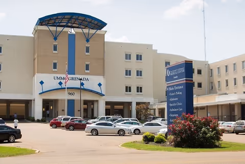 Front view of University of Mississippi Medical Center Grenada building with parked cars.