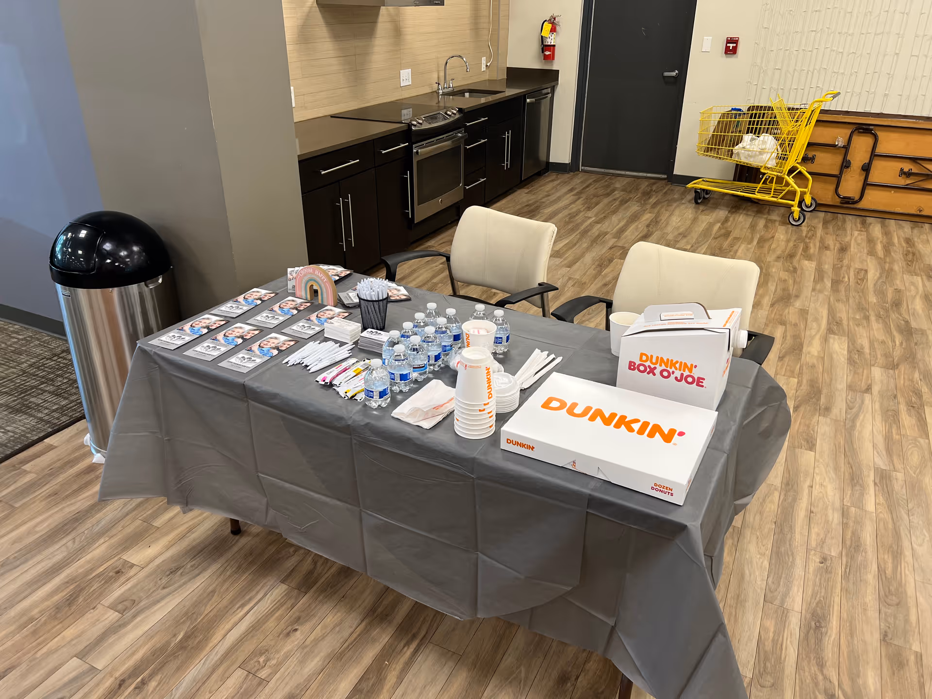 Registration table with Dunkin boxes, bottled water, and brochures in a senior living facility.
