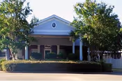 Front view of a single-story facility with a covered entrance and landscaped shrubs.