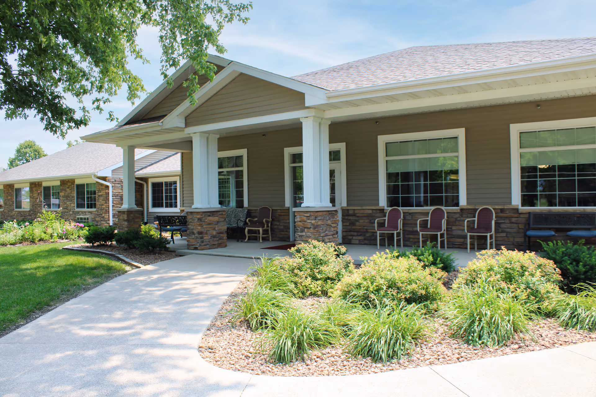 Exterior view of Hawkeye Assisted Living building with a covered porch and landscaped grounds.
