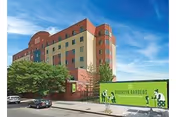 Exterior view of Brooklyn Gardens Nursing and Rehabilitation Center with a green construction fence.