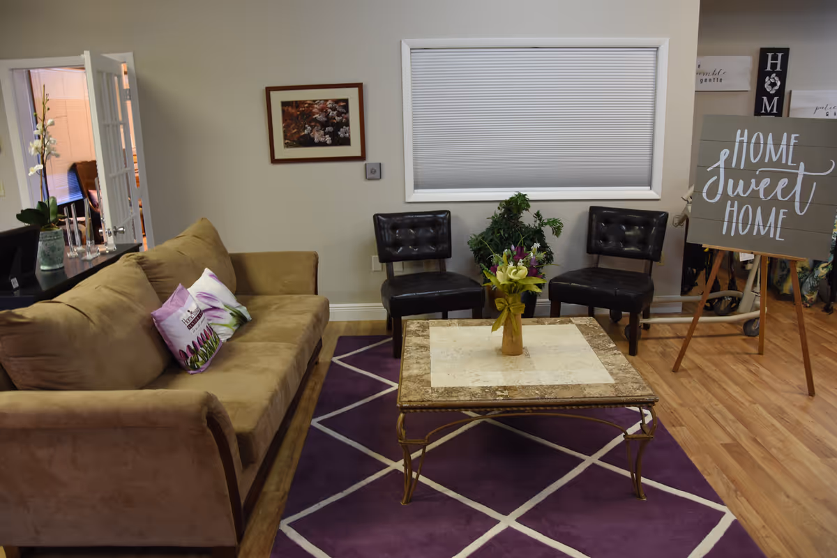 Cozy living room area with beige sofa, two black chairs, marble coffee table, and purple rug.