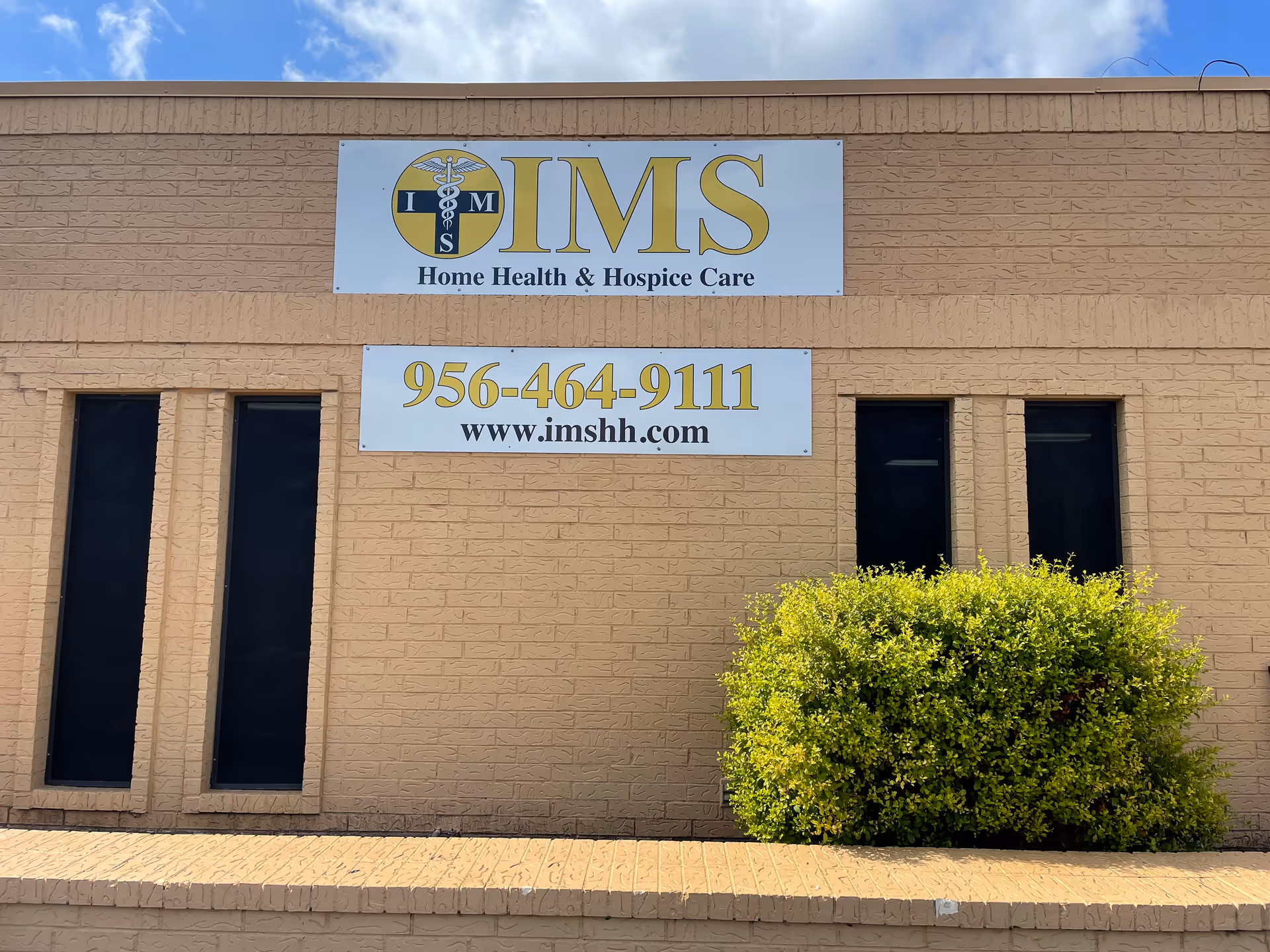 Front exterior of IMS Home Health & Hospice Care building with signage and bushes.