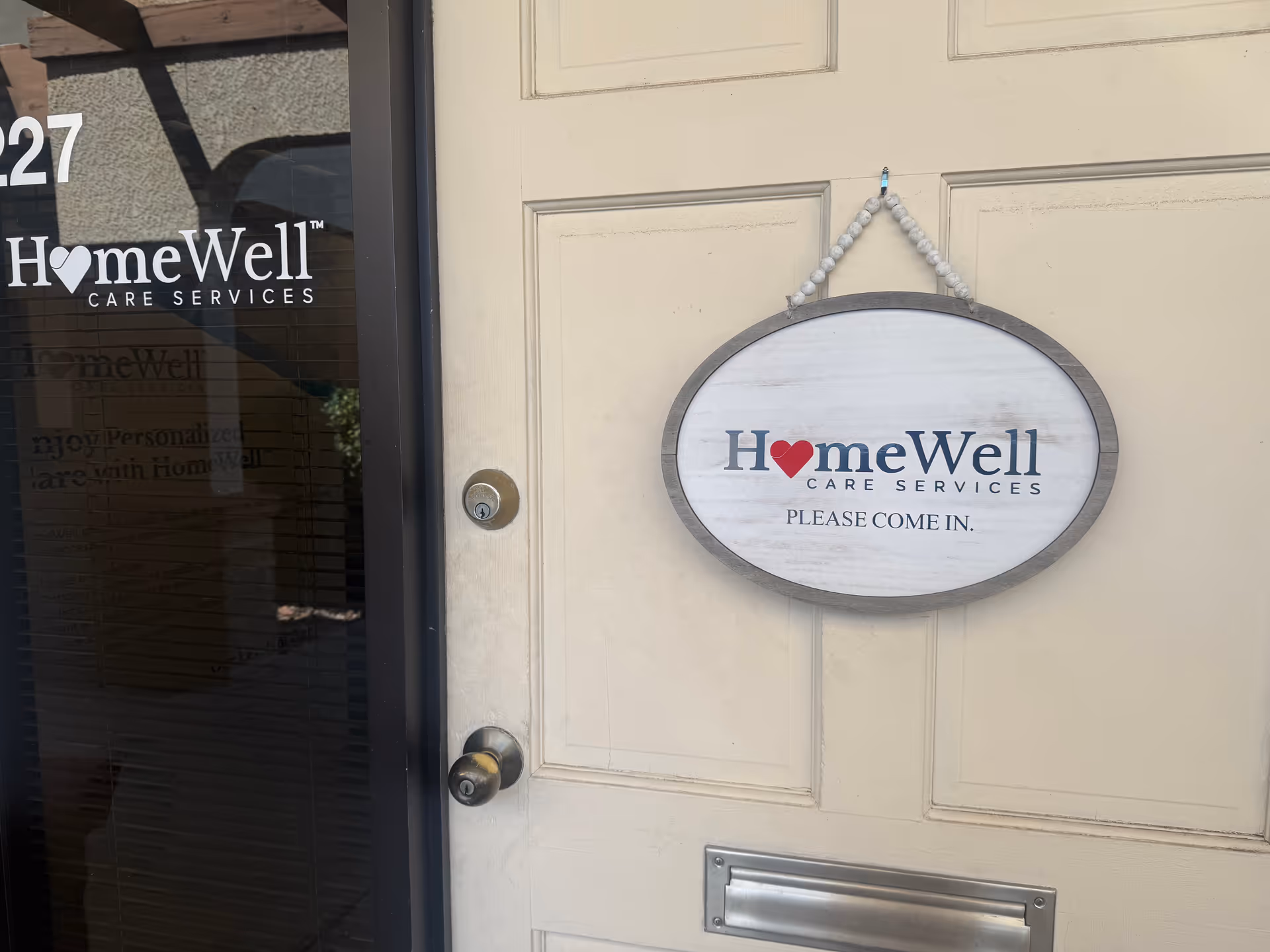 Entrance door with HomeWell Care Services sign hanging beside it.