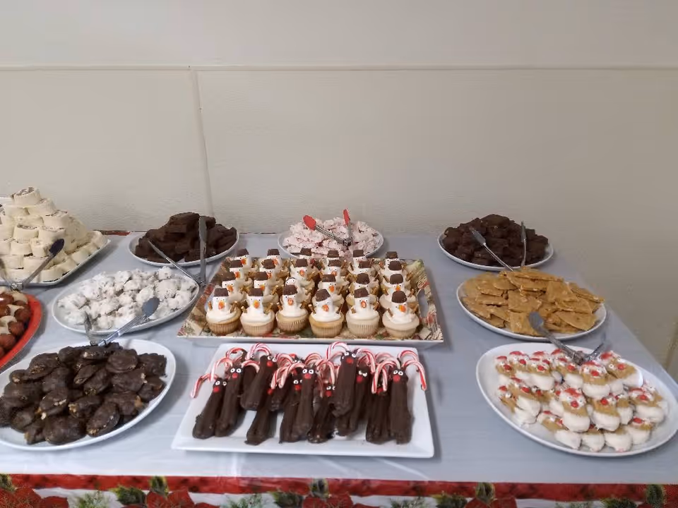 Indoor dessert table displaying assorted cookies, candies, and pastries.