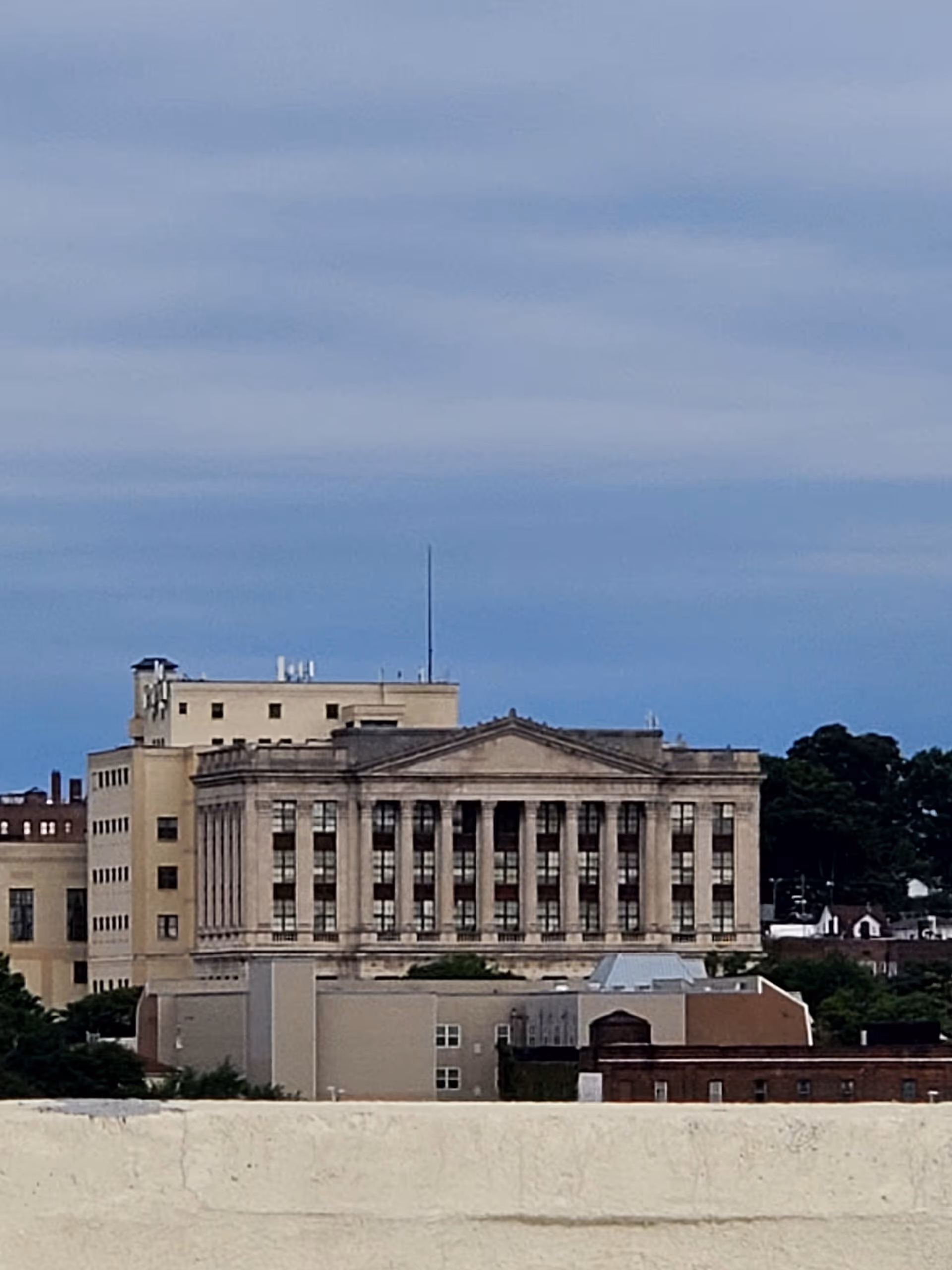 Front view of a large beige columned building against a blue sky.