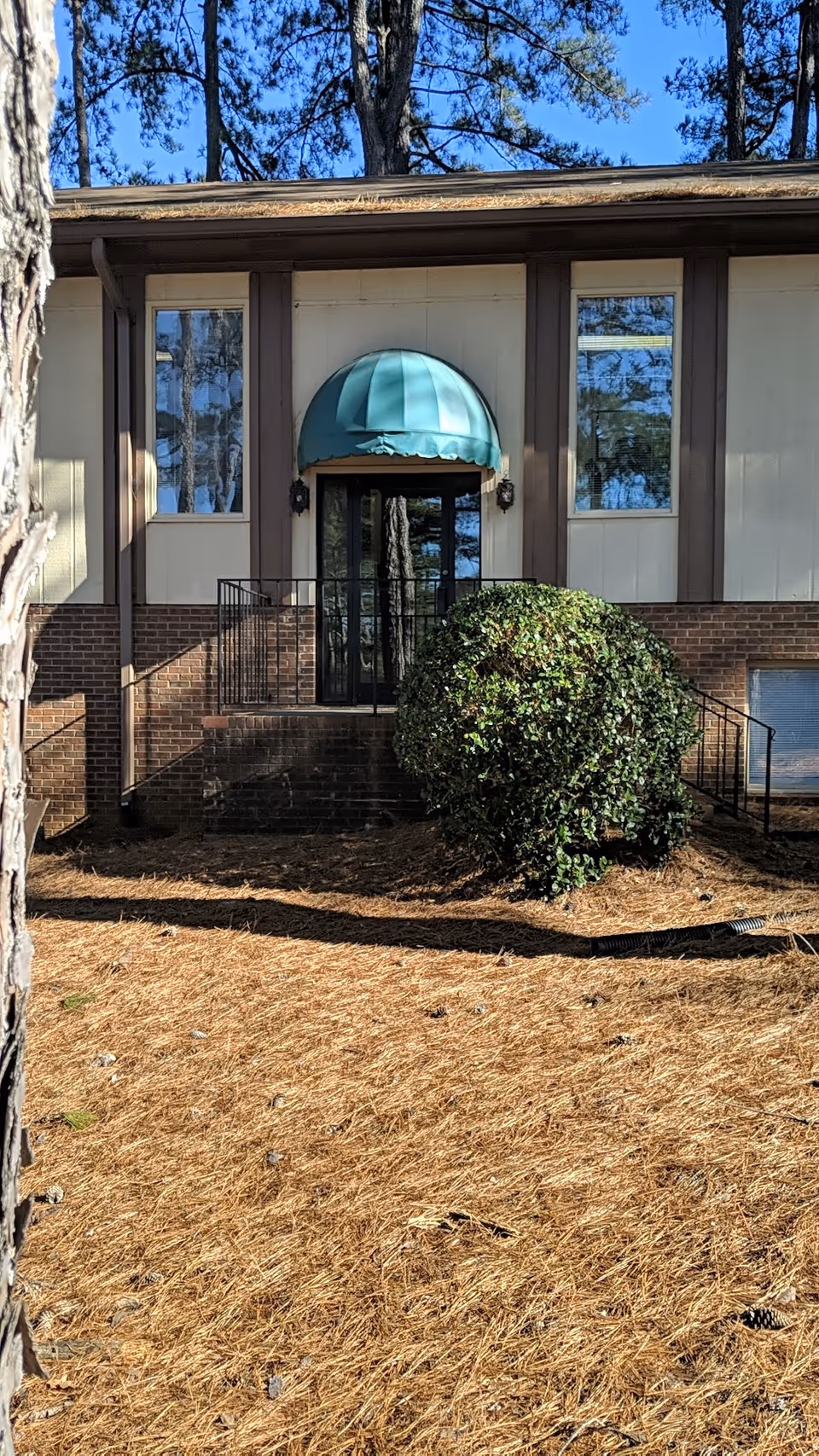Exterior view of JJ Home Care facility entrance with teal canopy and shrubbery.