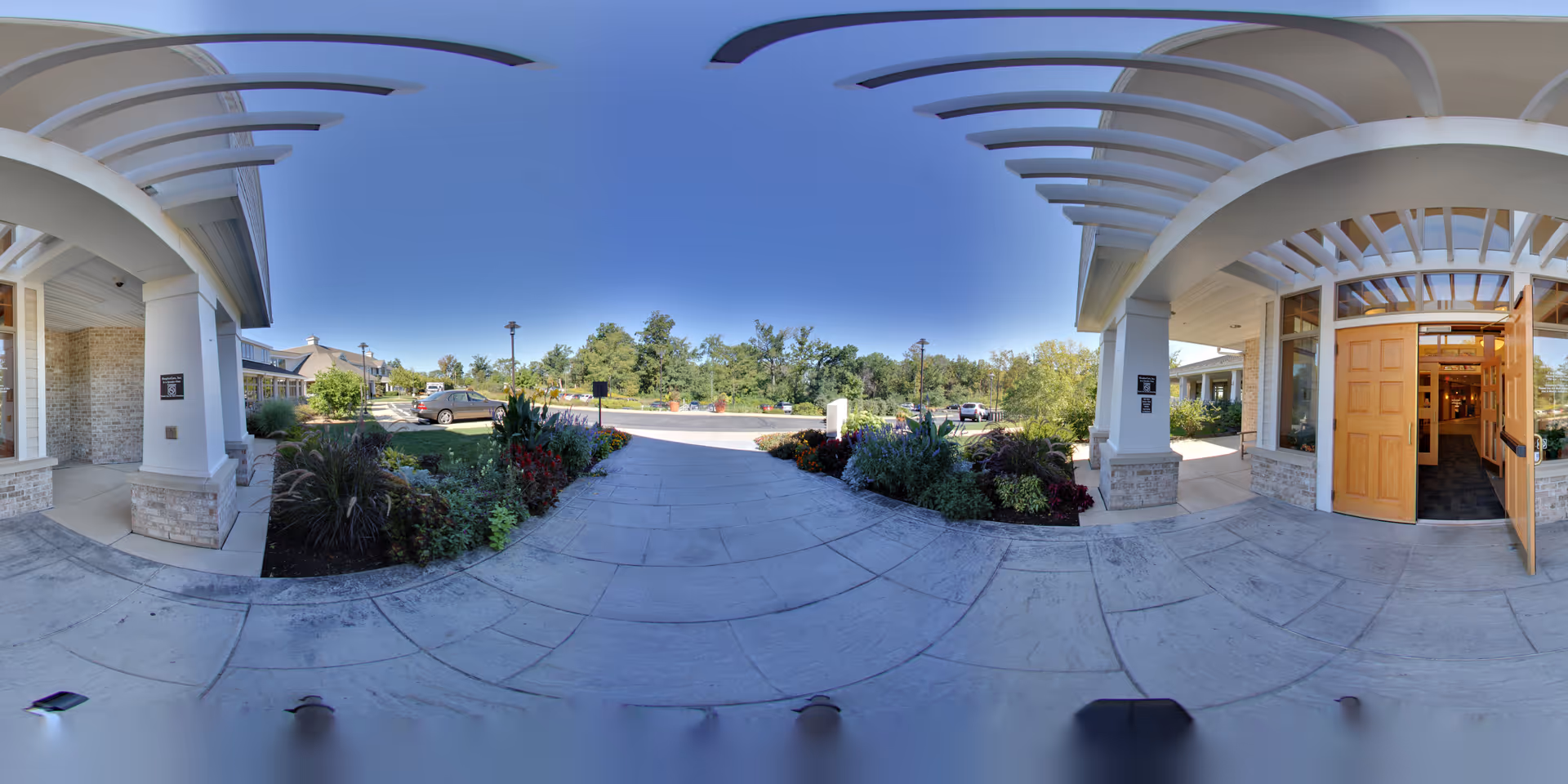 Entrance of Agrace senior living facility with curved white canopy and landscaping.