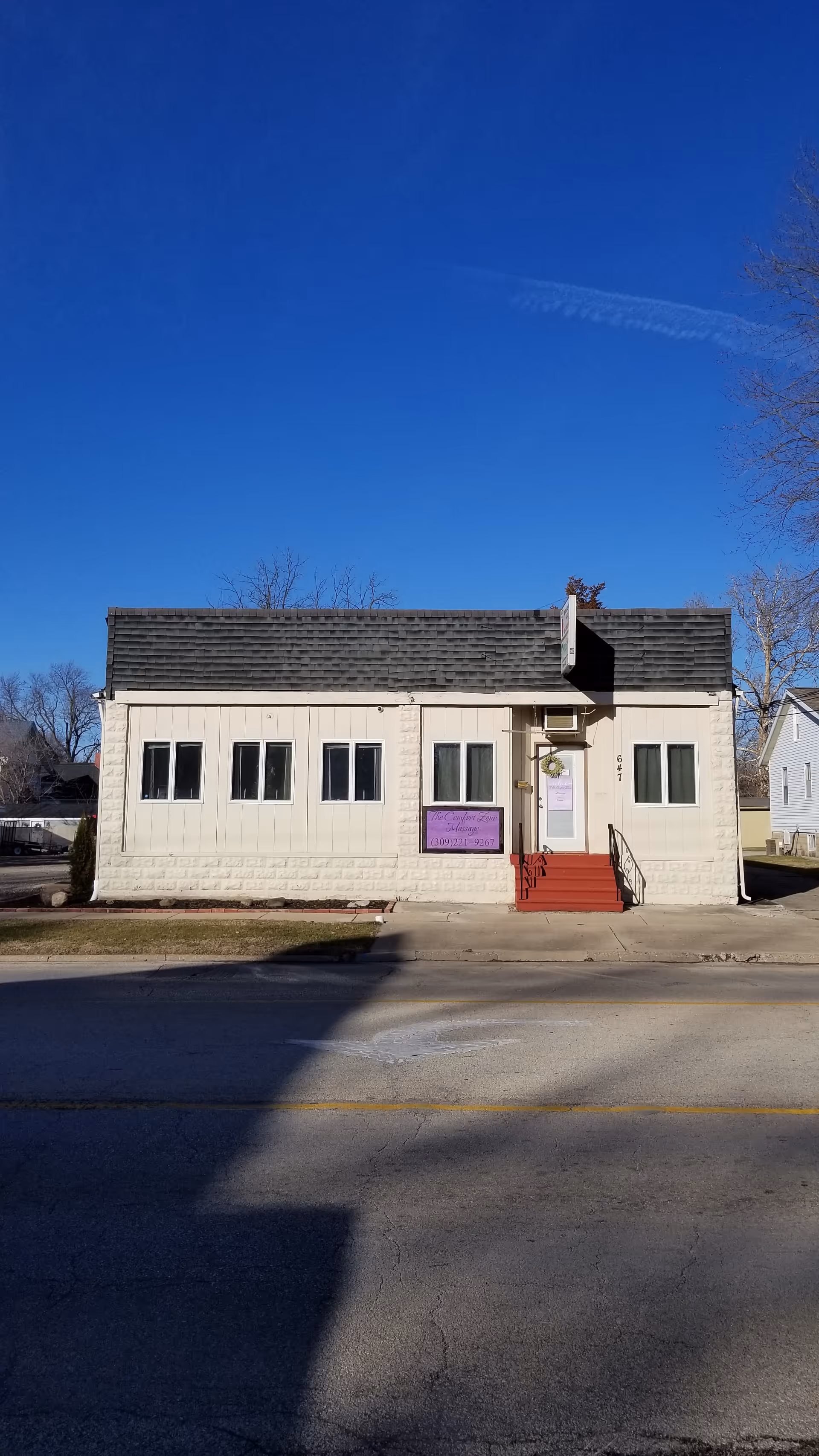 Single-story white building with red steps and a purple sign on the front.