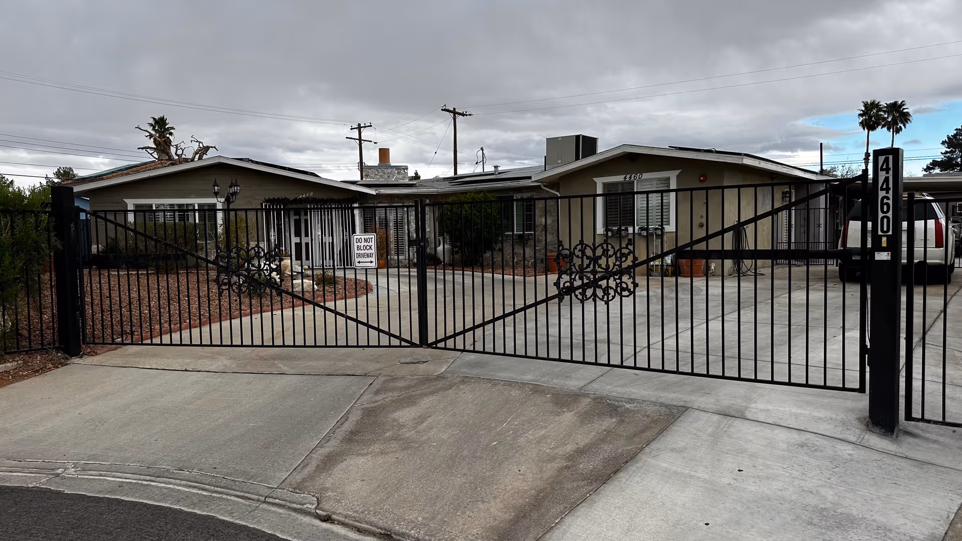 Gated driveway leads to a single-story care home behind a decorative iron gate.