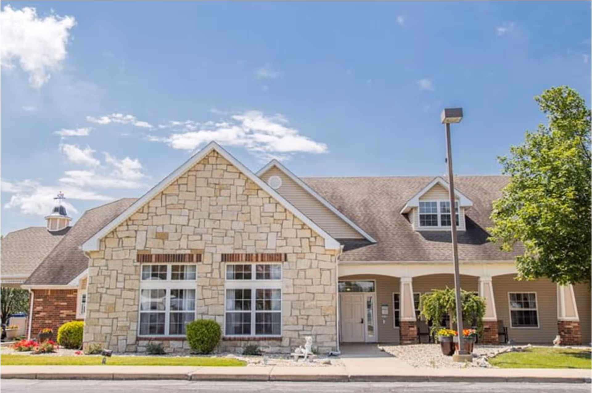 Front exterior of Kokomo Place senior living facility with stone facade and entrance.