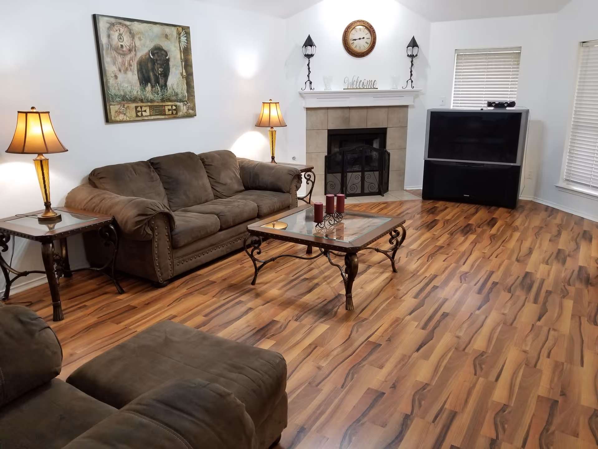 Cozy living room with brown couches, coffee table, fireplace, and large TV.