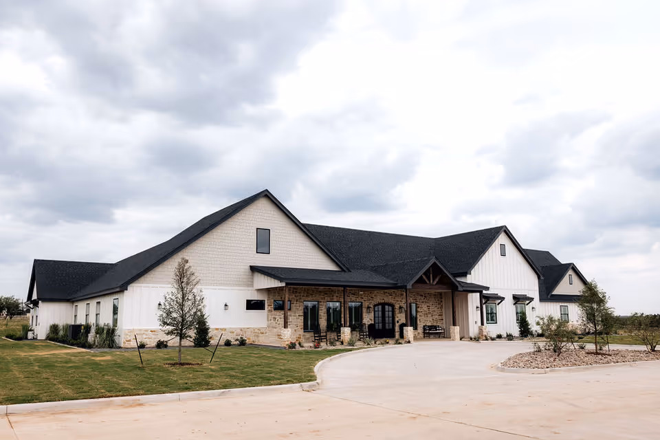 Exterior view of a modern assisted living facility with stone accents and a curved driveway.