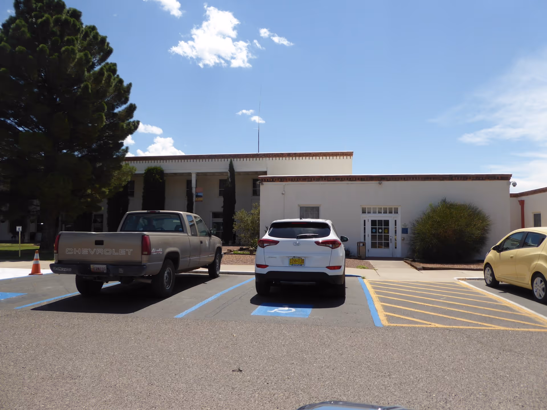 Front view of New Mexico State Veterans Home with parked cars and blue sky.