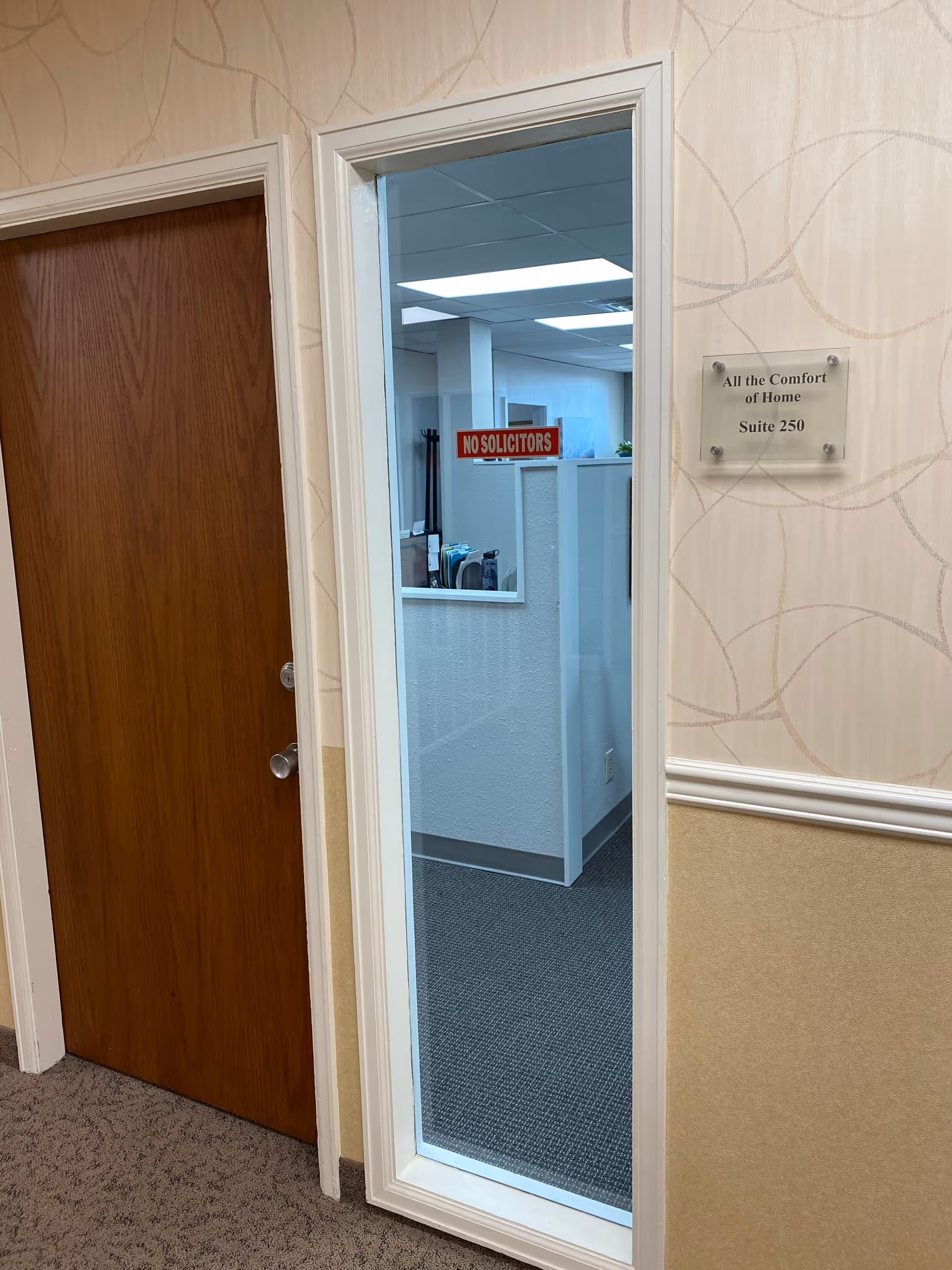 Interior hallway of All The Comfort Of Home, with door, plaque, and no solicitors sign.