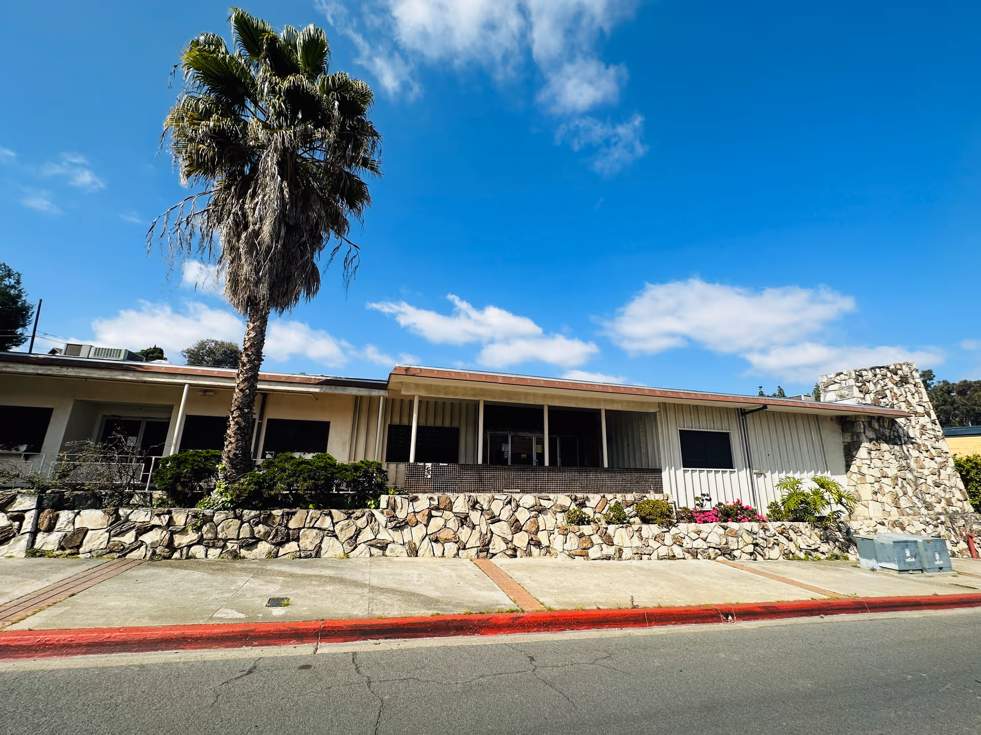 Front exterior of Hilldale Habilitation Center with a palm tree and blue sky.