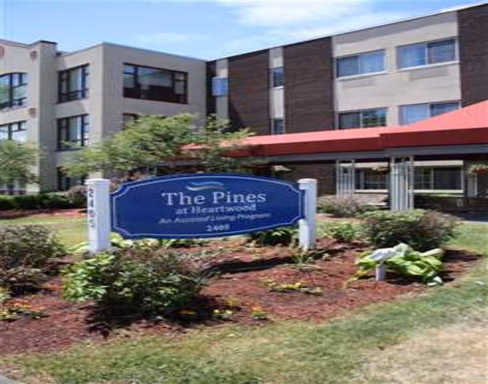 Front view of The Pines at Heartwood Assisted Living with garden and sign.