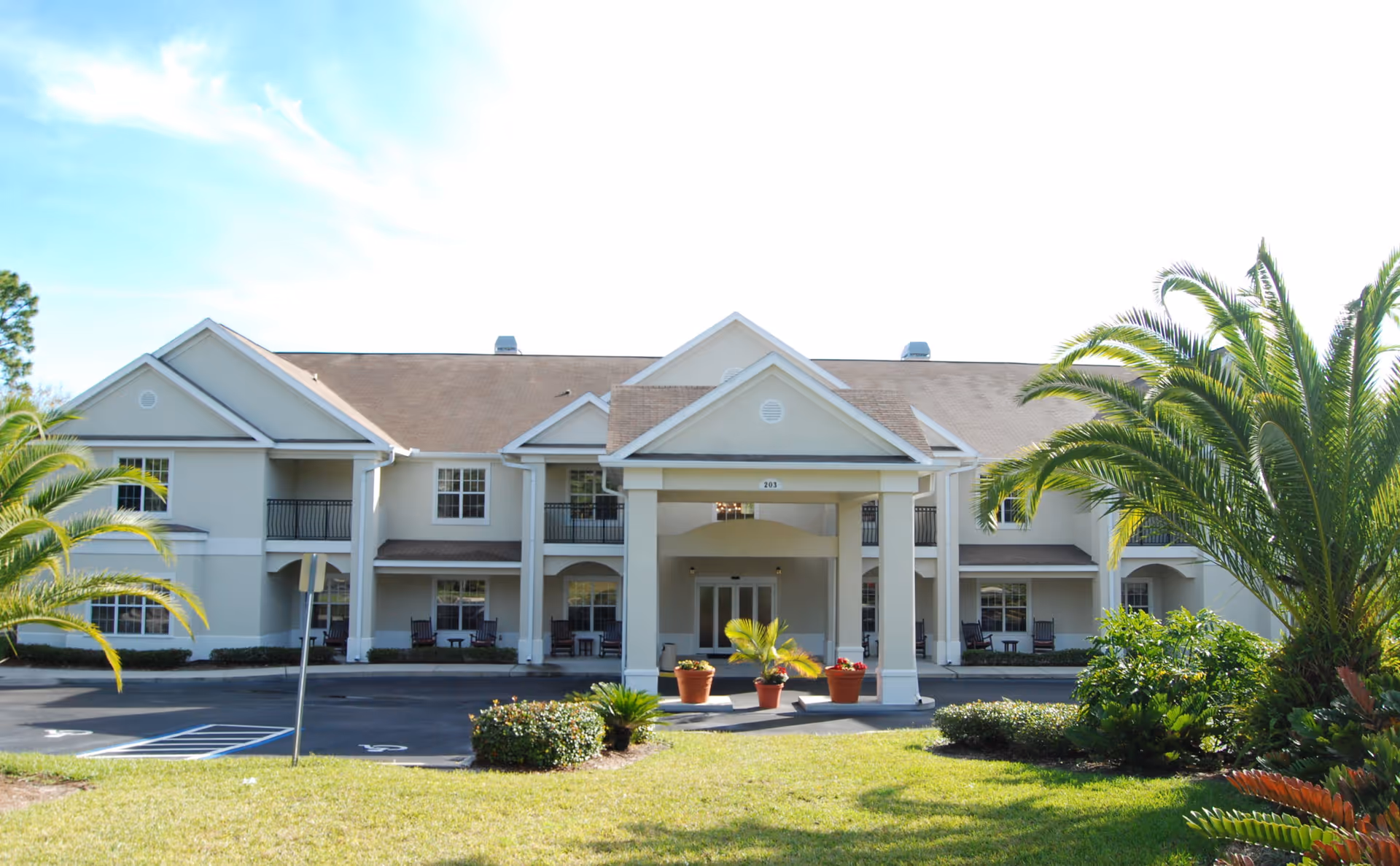 Exterior view of Brookdale Wekiwa Springs senior living center with a covered entrance and palm trees.