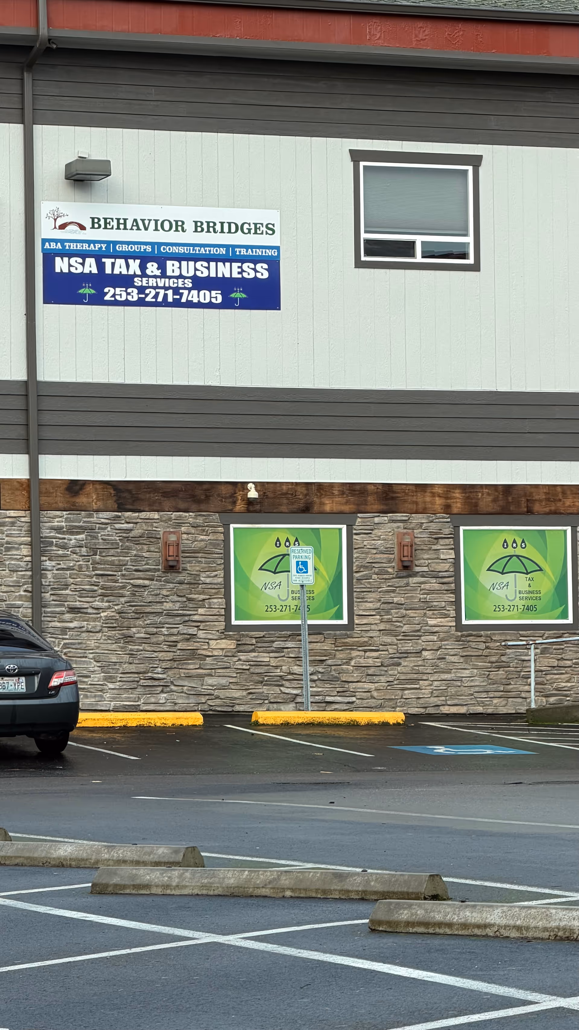 Exterior facade of a building with a Behavior Bridges sign and a parking lot.