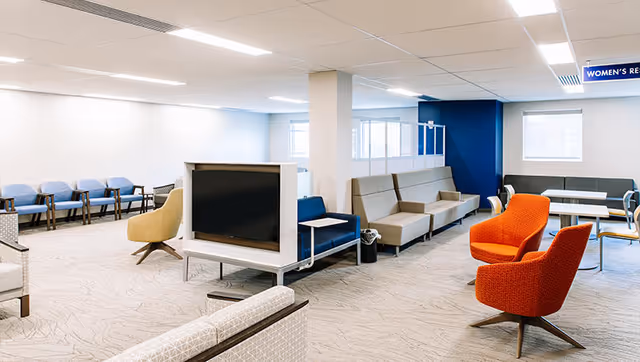 A bright, modern interior lounge with varied seating, a TV, and blue accent walls.