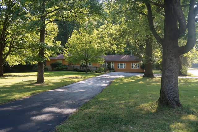 Esther's Place exterior: a single-story orange building with a curved driveway and trees.