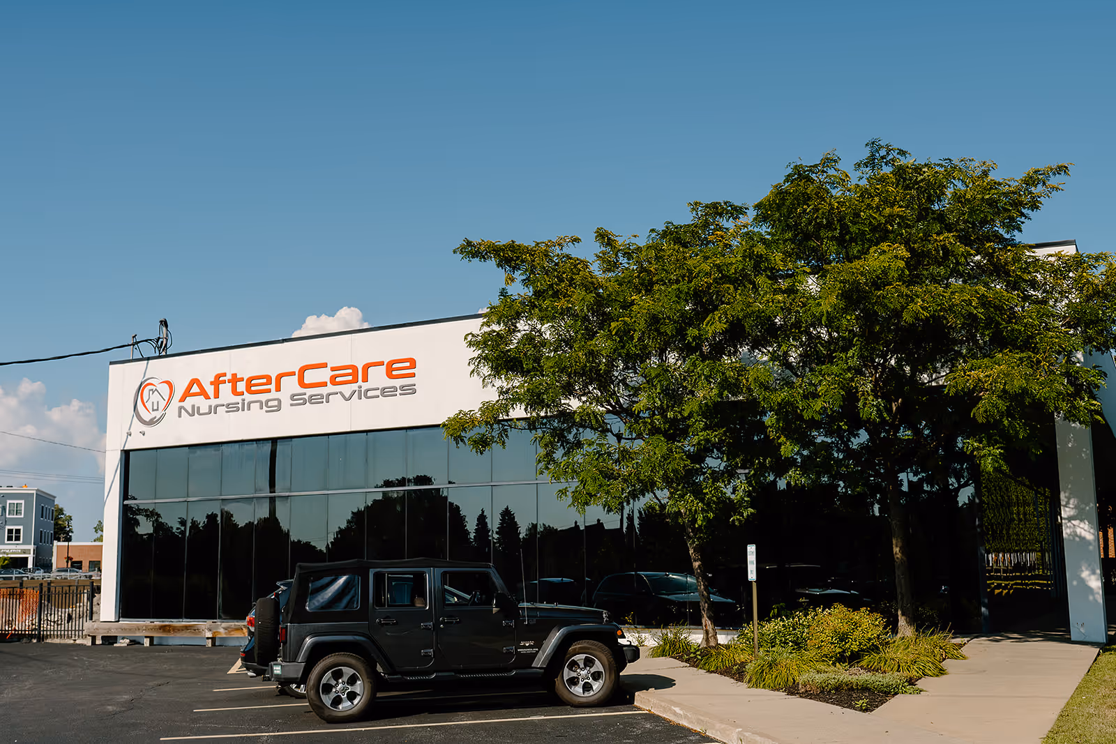 Front view of AfterCare Nursing Services building with glass windows and trees