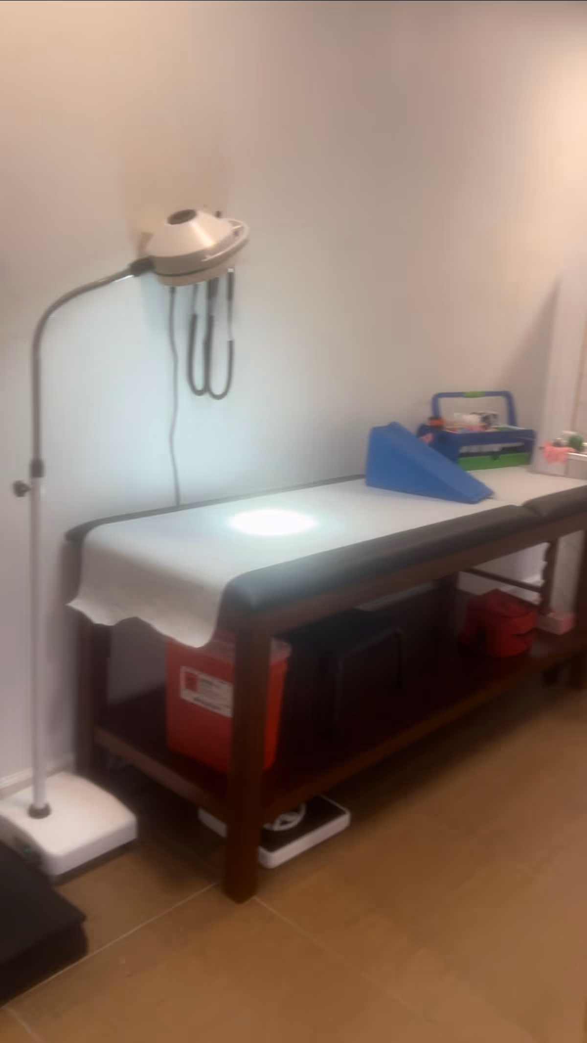 A medical examination table with supplies in a small, sterile clinic room.