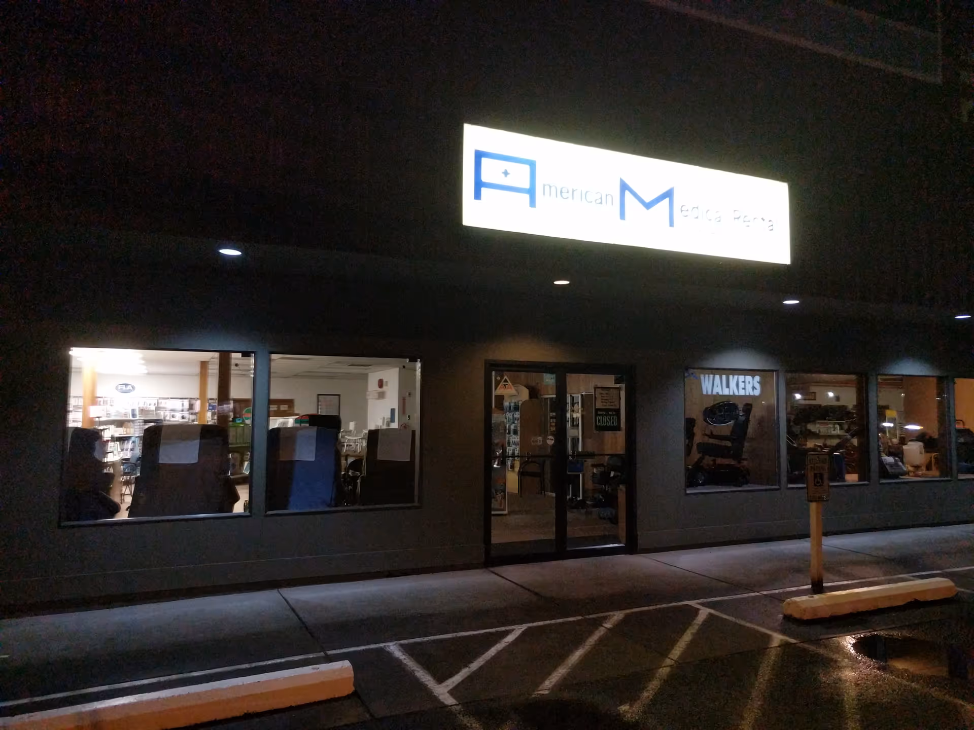 Night exterior of American Medical Rental and Supply storefront, illuminated sign visible.