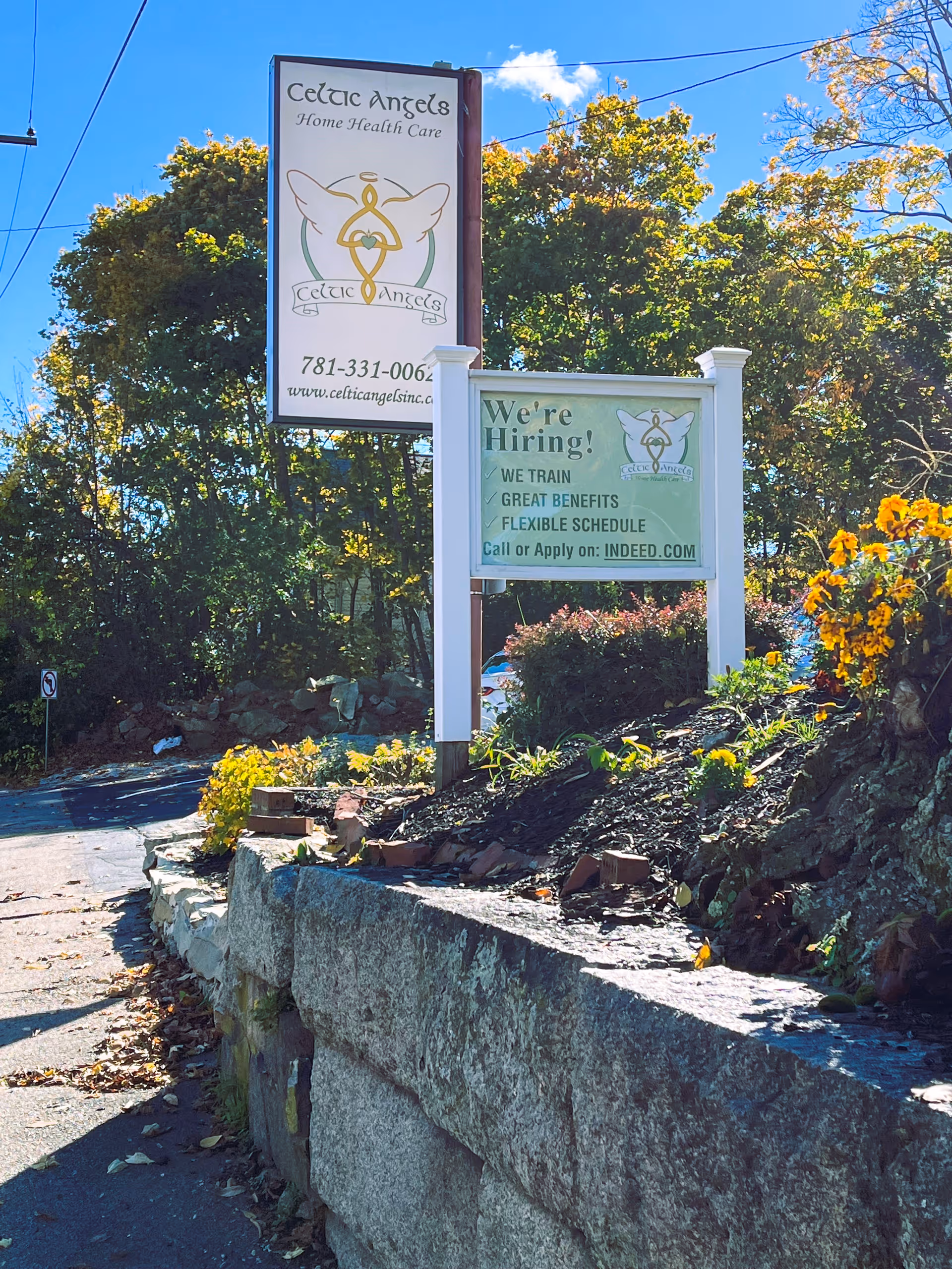 Outdoor signs for Celtic Angels Inc. beside a landscaped stone barrier.