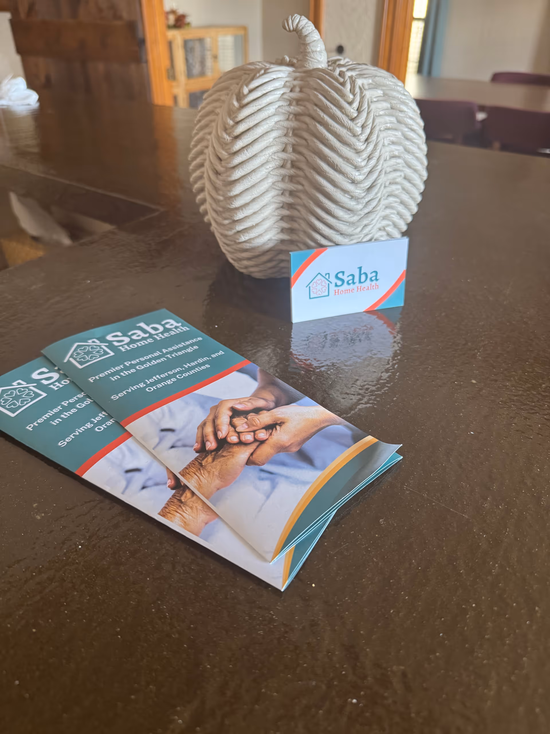 Brochures and a Saba Home Health card on a dark table.