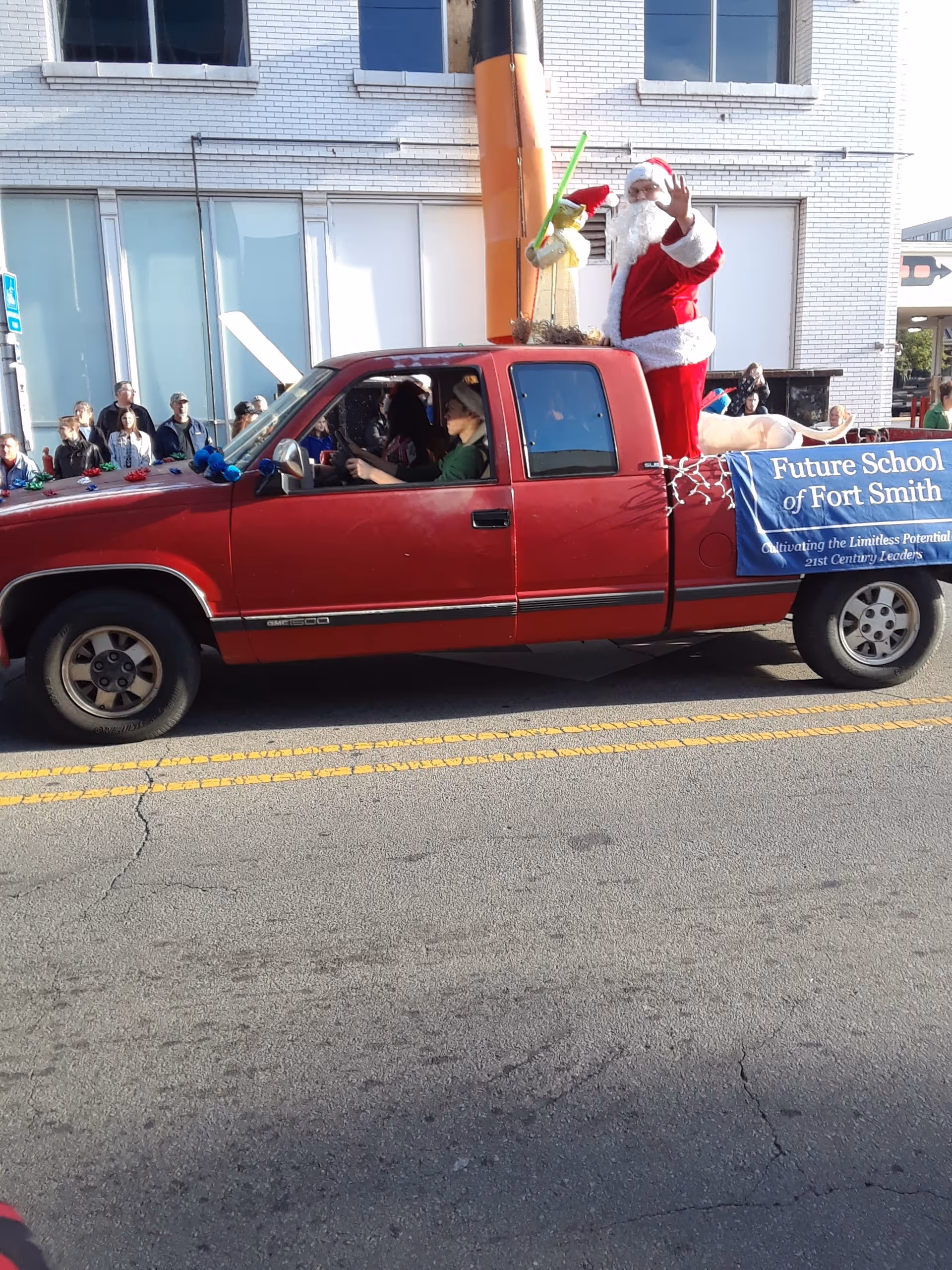 Red pickup truck with Santa standing on the back, in a street parade.