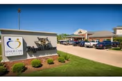 Front exterior of Pilgrim Manor Skilled Nursing and Rehabilitation with sign and parked cars.
