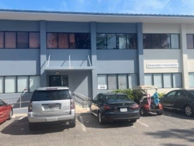 Exterior of a blue-gray senior care facility with parked cars in front.