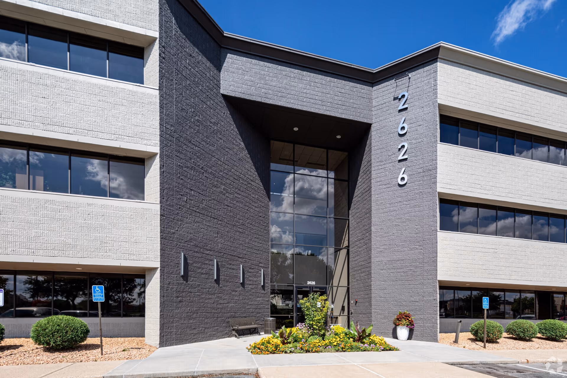 Modern, multi-story senior living building exterior with glass entrance and landscaped front entryway.