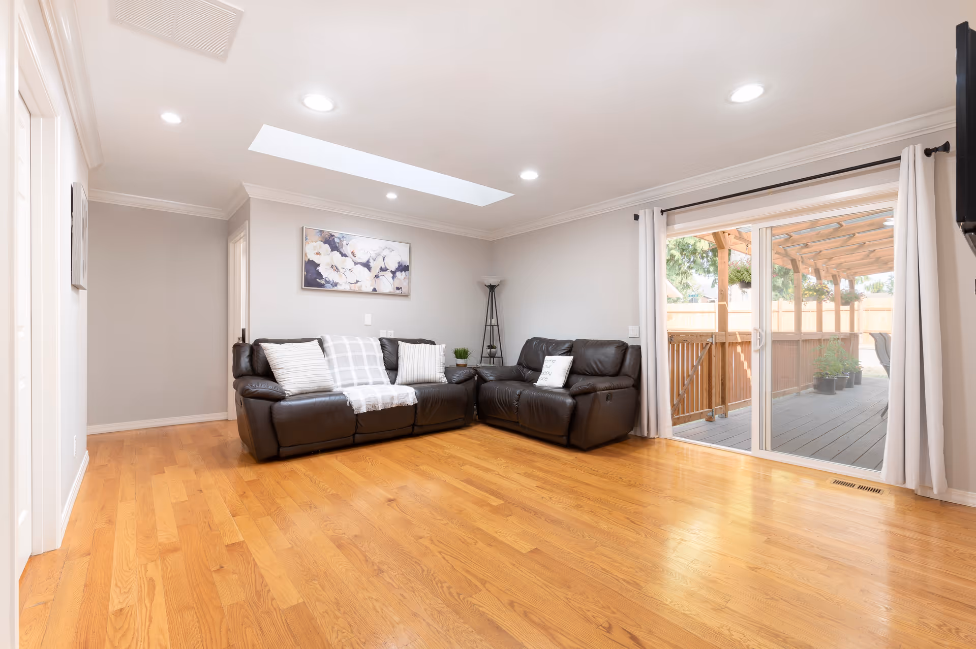 Bright living room featuring a leather sectional, skylight, and sliding door to a deck.