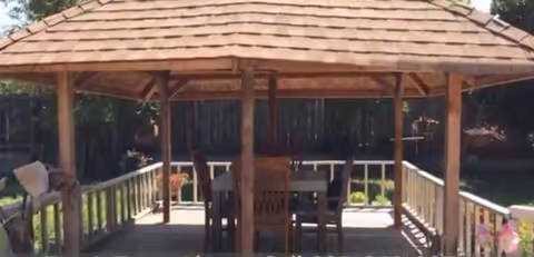 Wooden gazebo with a dining table and chairs on an outdoor deck.