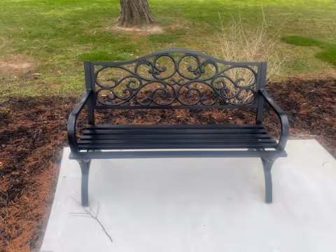 Ornate black metal bench on a concrete outdoor patio.
