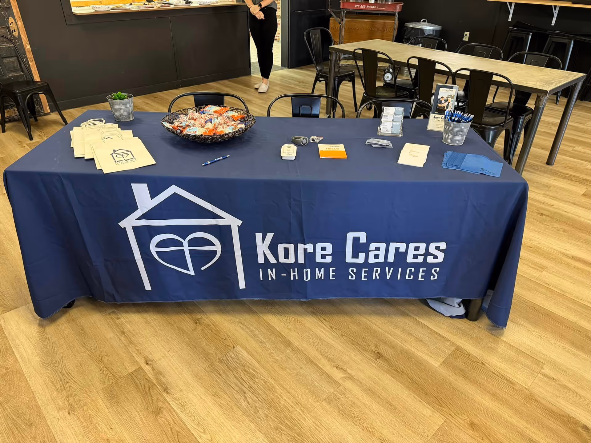 A promotional table with a Kore Cares banner sits inside a facility's interior.