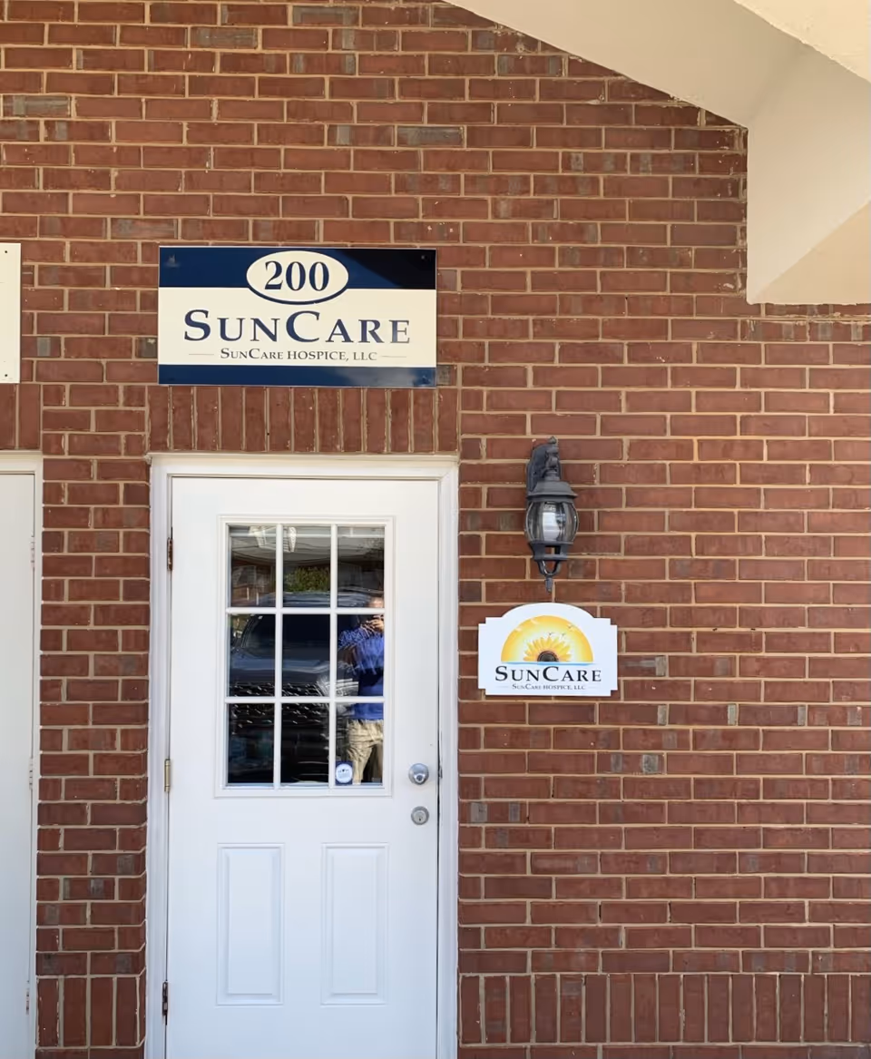 Front brick building exterior with a white door and SunCare Hospice sign.
