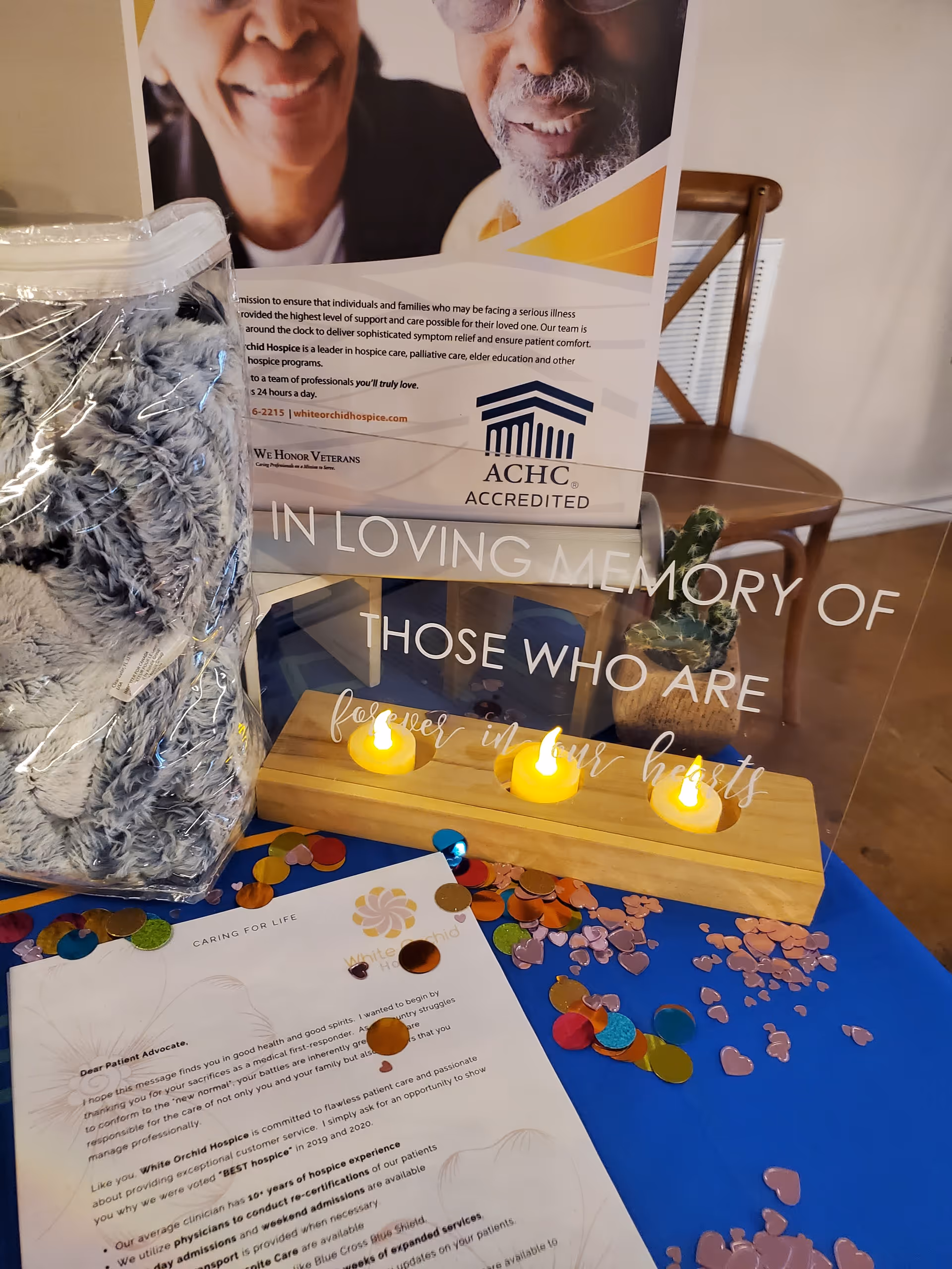 Interior memorial display with candles, confetti, and a banner for White Orchid Hospice.