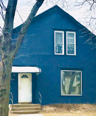 Blue two-story building exterior with white-trimmed windows and front steps.