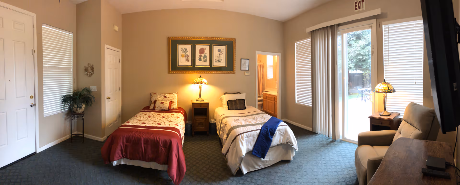 Two twin beds with matching lamps flank a central nightstand in a cozy, hotel-style bedroom.