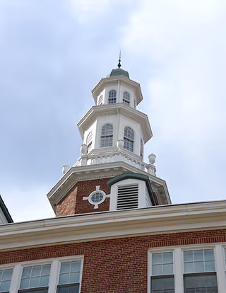 Exterior view of a brick building with a cupola against a blue sky.