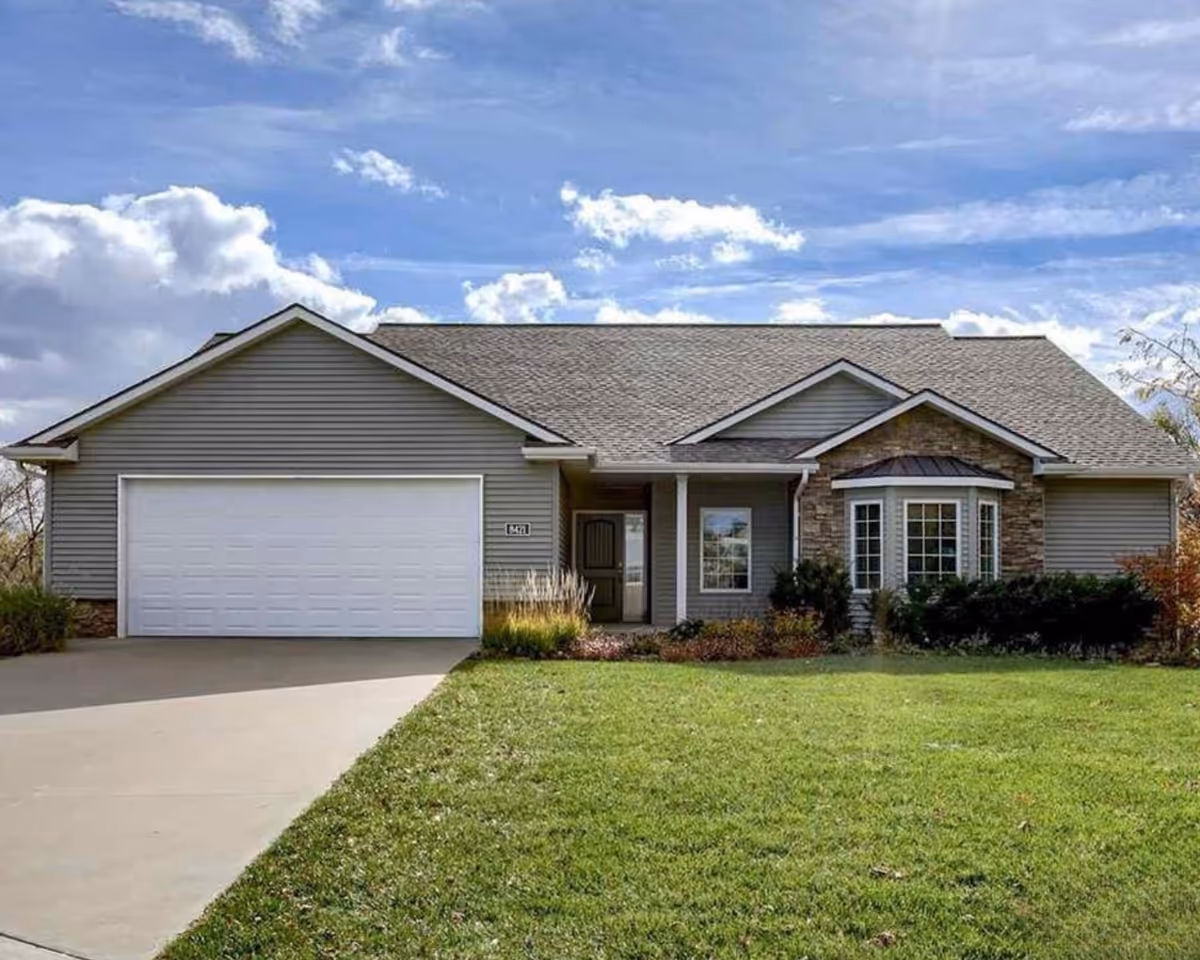 A single-story gray suburban house with a two-car garage and well-kept front lawn.
