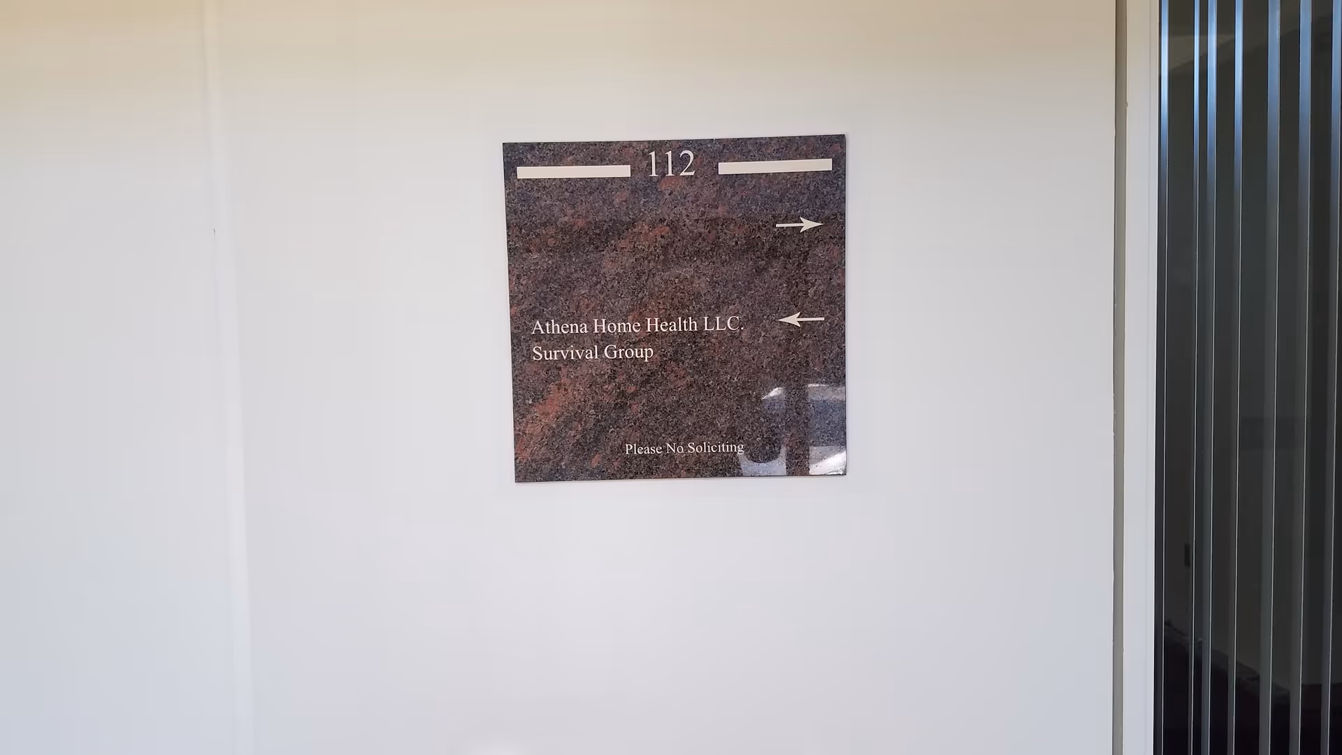 Dark granite plaque labeled 112 mounted on a white interior wall.