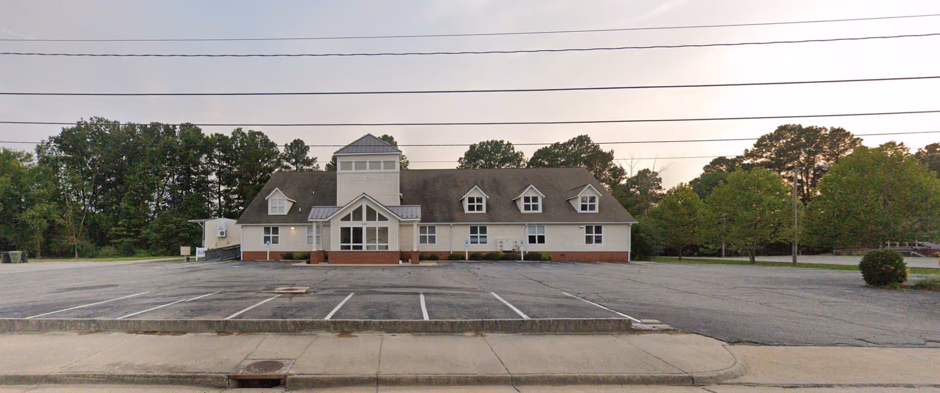 Front exterior of a two-story senior living facility with a tower and parking lot.