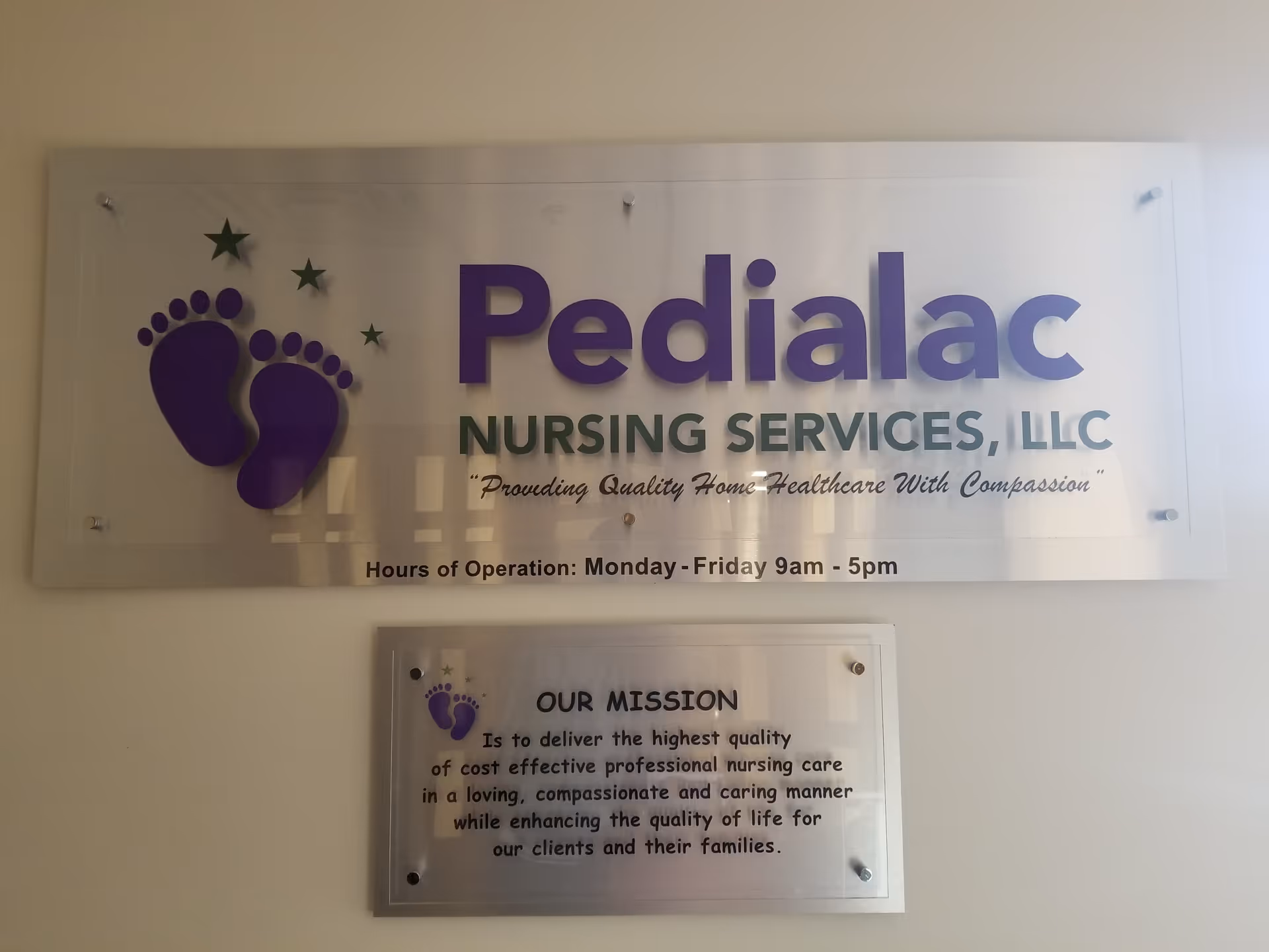 Interior wall sign reads Pedialac Nursing Services, LLC with purple footprints logo and mission plaque.